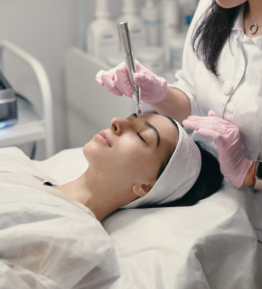 Model with closed eyes and hand's of doctor. Rejuvenating facial treatment. Model getting lifting therapy massage in a beauty SPA salon. Cosmetological clinic, procedure.