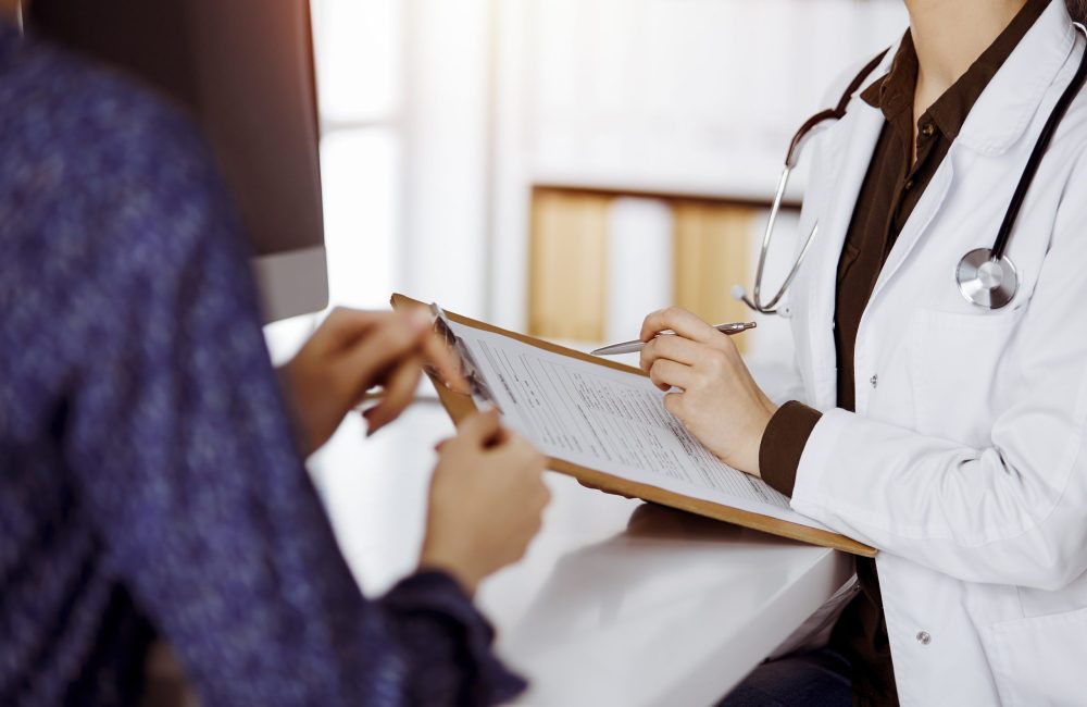 Doctor and patient discussing current health examination while sitting in sunny clinic. Perfect medical service in hospital.