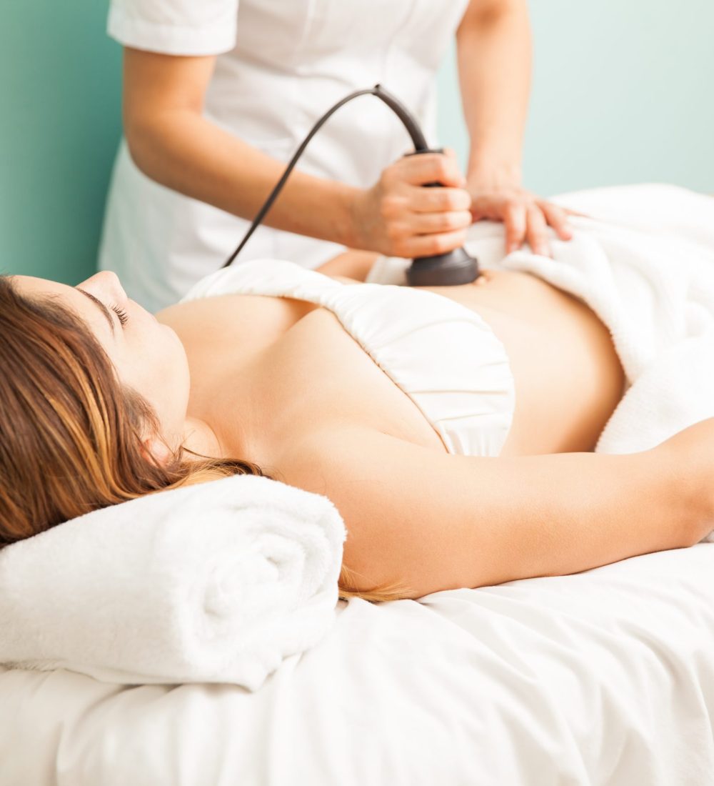 Female therapist giving a reductive and reaffirming treatment to a client and focusing on her belly