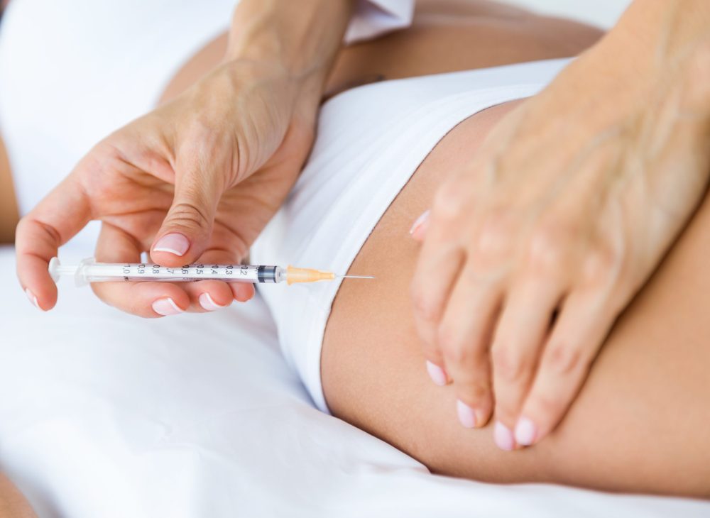Portrait of surgeon making injection into female body. Liposuction concept.